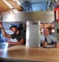 Researcher Robert Englar (right) and co-op student Daniel Hegeman adjust blowing slots on a model truck inverted in GTRI's low-speed wind tunnel. The testing helped assess the value of fuel-saving improvements.