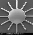 Researchers are developing a new class of tiny mechanical devices containing vibrating, hair-thin structures that could be used to filter electronic signals in cell phones and for other more exotic applications. The work is done inside a vacuum chamber sitting on top of a special vibration-absorbing platform critical to making the precise measurements. A tiny prototype, roughly comparable in size to a grain of sand, is pictured on the monitor at right. The device is an example of a microelectromechanical system, or a MEMS, which contains tiny moving parts.