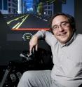 Stanford Professor Clifford Nass, seated at a car simulator in the Communication Between Humans and Interactive Media Lab, is studying the information flow between driver and car.