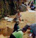 This image shows the 
excavation team working just inside the entrance 
to the Andrahomana Cave in Madagascar in 2003. 
In the right foreground, retired Malagasy 
professor Ramilisonina examines bones being 
uncovered by Mirya Ramarolahy. (Center) Lydia 
Raharivony and Leslie Seltzer talk about the 
work.  In the background (left to right) are Mara 
and Sambo and Laurie Godfrey.