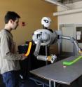 Assistant professor Alexander Stoytchev (right) and graduate student Jivko Sinapov are working to develop software so a robot can learn to use tools. One example of such learning is maneuvering a hockey stick around a puck.