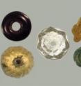 On the top left is a French manganese black opaque bead, some created with the <i>a speo</i> process. Below that is a Spanish spherical dot-incised gilded glass bead (6 found).  Next to those is a cut crystal, potentially manufactured in Spain because of inferior quality to known beads from France or Venice (6 found, as well as other nonglass beads of carnelian, jet and amber). Next to that on top is a unique yellow melon shaped bead, possibly from China. Below that is a Chinese wound translucent-transparent green (4 found). Finally on the far right is a blown black bead with greenish-yellow dots (13 found with one burial that are potentially French).