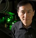 Chunlei Guo uses the femtosecond laser (behind him) to create nanostructures in metal that can move liquid uphill.