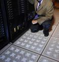 Georgia Tech Professor Yogendra Joshi shows perforated floor tiles from the cold-aisle used to supply chilled air from beneath the floor of a simulated server room. The chilled air is entrained at the front of the server cabinets to provide cooling. Georgia Tech Professor Yogendra Joshi shows perforated floor tiles from the cold-aisle used to supply chilled air from beneath the floor of a simulated server room. The chilled air is entrained at the front of the server cabinets to provide cooling.