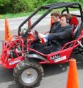 Mark Riccobono, executive director of the National Federation of the Blind’s Jernigan Institute, drives the Virginia Tech Blind Driver Challenge vehicle through an obstacle course of traffic cones on a campus parking lot. In the passenger seat is Greg Jannaman, who led the student team within the mechanical engineering department during the past year, and is monitoring the software of the vehicle.