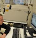 UC Riverside's Chris Reinhard analyzes metal content in 2.5 billion-year-old black shale using a mass spectrometer seen to his left.