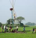 Rebecca Neumann (in green hat) works with graduate students from the Harvey Lab, technicians from the Bangladesh University of Engineering and Technology and local people to install a 20-foot tower in a rice field near Bashailbhog village in Bangladesh. The tower housed a datalogger and battery that powered, controlled and recorded data collected hourly by 18 hydrologic sensors installed at a range of depths below the rice field surface. The tower, red cage and waterproof box were necessary to keep the equipment above the annual monsoon floods, which may be as deep as 15 feet. Neumann periodically climbed the tower carrying a laptop computer to download data off of the datalogger.