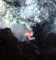An explosion at the West Mata Volcano throws ash and rock, with molten lava glowing below.