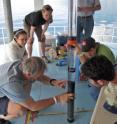 Researchers and students examine a sediment core sample from the bottom of Guatemala's high-mountain tropical Lake Atitlan to help trace the history of impacts on the lake's ecosystem. The lake’s water is contaminated with watershed runoff and waste water, which contributes to increased algae growth and suitable conditions for bacteria and pathogens that can proliferate and enter untreated drinking water