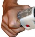 This is a close-up of a touch-based driving navigation device attached to the steering wheel of a driving simulator. The red button -- a TrackPoint computer mouse taken from an old IBM ThinkPad -- moves left or right to stretch the driver's index fingertip skin in the direction the driver should turn. The index finger is retracted from its normal position so the button can be seen. A University of Utah study found that navigation information can be delivered to drivers just as accurately through the fingertips as through the ears, although if a driver also is talking on a cell phone, they follow touch-based turning instructions more accurately than voice instructions.