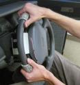 Two devices, mounted on the steering wheel of a driving simulator, convey navigation information (turn left or turn right) to the driver. The driver's index fingertips rest on two IBM ThinkPad TrackPoint buttons (not visible) that move left or right by about 1 millimeter (a twenty-fifth of an inch) to tell the driver which way to turn.