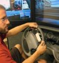 Nate Medeiros-Ward, a University of Utah psychology doctoral student, operates a driving simulator with a steering wheel equipped with two touch devices that pull the skin on his index fingertips left or right (counterclockwise or clockwise) to tell him which way to turn. A new University of Utah study found that navigation information can be conveyed to a driver through the fingertips as accurately as through audio instructions from a navigation system. And when drivers are distracted by talking on a cell phone, the fingertip instructions are followed more accurately than audio instructions. The touch-based devices could help improve safety for motorists and hearing-impaired drivers, and also lead to navigational canes that provide navigation information to blind pedestrians.