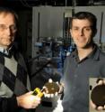 Scientists Orest Glembocki (holding a DeltaNu ExamineR hand-held Raman spectrometer) and Joshua Caldwell, display one of the silicon wafers they fabricated for the SERS sensing using ion etching and e-beam lithography. Several square arrays of gold-coated silicon nanopillar were fabricated on the wafer to perform surface-enhanced Raman scattering testing.
