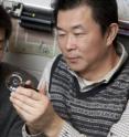 Two Ohio State University engineers inspect a lens that enables microscopes to capture 3-D images. Shown from left to right are inventors Lei Li, a postdoctoral researcher, and Allen Yi, associate professor of integrated systems engineering.