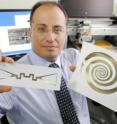 Georgia Tech School of Electrical and Computer Engineering professor Manos Tentzeris holds a sensor (left) and an ultra-broadband spiral antenna for wearable energy-scavenging applications.  Both were printed on paper using inkjet technology.