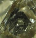 Below this diamond's surface is a hexagonal grain of iron sulfide surrounded by a black rim.