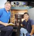 Paul Steffes, a professor in Georgia Tech's School of Electrical and Computer Engineering, poses with a pressure vessel used to simulate the atmosphere of Jupiter.  With him is graduate student Danny Duong.