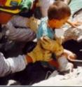 A child is rescued from beneath collapsed concrete.