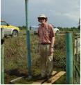 Subsidence pole inserted in peatland in Johor, peninsular Malaysia. The pole was inserted beside an oil palm plantation in 1978 and at the time of this photograph (2007), 2.3 m of subsidence had occurred (the human "measuring stick," Dr. Chris Banks, is 2 meters tall).