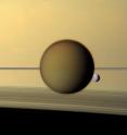 Titan's dense atmosphere shrouds the moon beneath a tan haze in this image. Saturn's third-largest moon Dione can be seen through the Titan haze in this view of the two posing before the planet and its rings from NASA's Cassini spacecraft. The rings, viewed nearly edge-on, appear as a horizontal line through the image. The rings cast shadows on Saturn, which appear as dark lines at the bottom of the image. The Cassini spacecraft narrow-angle camera made this image on May 21, 2011, at a distance of approximately 1.4 million miles (2.3 million kilometers) from Titan. Titan's dense atmosphere shrouds the moon beneath a tan haze in this image. Saturn's third-largest moon Dione can be seen through the Titan haze in this view of the two posing before the planet and its rings from NASA's Cassini spacecraft. The rings, viewed nearly edge-on, appear as a horizontal line through the image. The rings cast shadows on Saturn, which appear as dark lines at the bottom of the image. The Cassini spacecraft narrow-angle camera made this image on May 21, 2011, at a distance of approximately 1.4 million miles (2.3 million kilometers) from Titan.