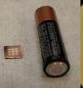 Left: Each dark speck within the nine white circles at left is a tiny fuel cell. An AA battery is shown for size comparison. Right: One of the nine circles is magnified in this image, showing the wrinkled surface of the electrochemical membrane.