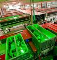 This shows the BELLA laser under construction. In the foreground, units of the front end stretch and amplify short, relatively weak laser pulses before further amplification in the long central chamber. Amplification is done by titanium sapphire crystals boosted by a dozen pump lasers. At the far end of the hall the now highly energetic stretched pulse is compressed before being directed to BELLA’s electron-beam accelerator component.