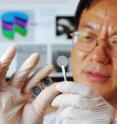 Georgia Tech researcher Zhong Lin Wang holds the components of a new self-charging power cell that uses piezoelectric materials to directly convert mechanical energy to chemical energy. The chemical energy can be released as electricity.