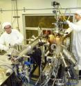 Inside a clean room, physicists Ivan Bozovic (left) and Anthony Bollinger, Brookhaven, work on the molecular beam epitaxy system that produced the atomically perfect materials used in the study.
