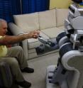 A robot hands a prescription bottle to a patient.