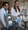 Facundo Fernandez (left) and Rachel Bennett, use a robotic arm to probe objects with irregularly-shaped surfaces for mass spectrometry.