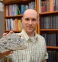 Professor Jonathan Payne holds up fossil brachiopods that are more than 400 million years old.
