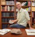 Professor Jonathan Payne holds up fossil brachiopods that are more than 400 million years old.