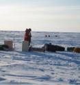 A scientist assembles an ice-tethered water profiler on the ice in March. The instrument is now anchored in a hole in the sea ice, with a moving piece to measure the water properties below.