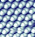 An image made with a scanning tunneling microscope shows hybrid buckydiamondoid molecules on a gold surface. The buckyball end of each molecule is attached to the surface, with the diamondoid end sticking up; both are clearly visible. The area shown here is 5 nanometers on a side.