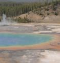 This is a photograph of Grand Prismatic Spring with people walking on boardwalk.