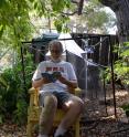 Glen Creason relaxing with an insect field guide in front of the insect trap and weather station that he hosts at his home for the Natural History Museum of Los Angeles County's BioSCAN project.