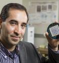 Masoud Agah, of Virginia Tech's Bradley Department of Electrical and Computer Engineering, is holding up a microelectrode array, used for real time electrical recording of cellular activity.