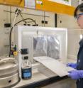Berkeley Lab research associate Sharon Chen sprays roofing material with soiling mixture.