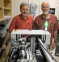 University of Utah geochemists Diego Fernandez and Thure Cerling stand behind a laser machine that blasts tiny samples off 'fish ear bones' as part of a new method of tracking salmon caught at sea to learn where they hatched and spent time. The tube in front of Cerling carries debris from the laser blasts to a mass spectrometer in another room. That device analyzes strontium-isotope ratios in the fish ear stones to reveal the life histories of the salmon.