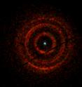 Rings of X-ray light centered on V404 Cygni, a binary system containing an erupting black hole (dot at center), were imaged by the X-ray Telescope aboard NASA's Swift satellite from June 30 to July 4. A narrow gap splits the middle ring in two. Color indicates the energy of the X-rays, with red representing the lowest (800 to 1,500 electron volts, eV), green for medium (1,500 to 2,500 eV), and the most energetic (2,500 to 5,000 eV) shown in blue. For comparison, visible light has energies ranging from about 2 to 3 eV. The dark lines running diagonally through the image are artifacts of the imaging system.
