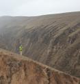 Geoscientist Fulong Cai stands on a linear ridge on top of China's Loess Plateau and looks across a river valley at another of the plateau's linear ridges. The high hills in the far background are on the edge of the plateau, which drops about 1,300 feet (400 meters) to the Mu Us Desert to the northwest.