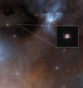 <p>The young star 2MASS J16281370-2431391 lies in the spectacular Rho Ophiuchi star formation region, about 400 light-years from Earth. It is surrounded by a disc of gas and dust -- such discs are called protoplanetary discs as they are the early stages in the creation of planetary systems. This particular disc is seen nearly edge-on, and its appearance in visible light pictures has led to its being nicknamed the Flying Saucer.

<p>The main image shows part of the Rho Ophiuchi region and a much enlarged close-up infrared view of the Flying Saucer from the NASA/ESA Hubble Space Telescope is shown as an insert.