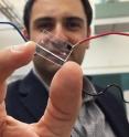 Fatih Sarioglu, an assistant professor in Georgia Tech's School of Electrical and Computer Engineering, holds a hybrid microfluidic chip that uses a simple circuit pattern to assign a unique seven-bit digital identification number to each cell passing through the channels.