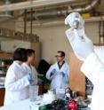 Martin Thuo holds a vial of the liquid-metal particles produced by his research group. Working behind him are, left to right, Simge Cinar, Jiahao Chen and Ian Tevis.