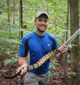 Matthew Holding holds a rattlesnake in the field in California