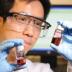 Georgia Tech professor Zhiqun Lin examines a gold nanoparticle toluene solution. The work is part of research on using star-shaped block co-polymers to create nanocrystals of uniform size and shape.