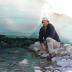 Mark Urban, associate professor of ecology and evolutionary biology at the University of Connecticut, stands under a sheet of aufeis in Alaska. These ice sheets form over Arctic underground springs but have become less prevalent with global warming.