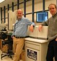 Penn State genomicists Webb Miller and Stephan C. Schuster in front of the Roche / 454 Life Sciences' Genome Sequencer 20 System that was used to sequence mammoth nuclear DNA.