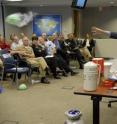 Nobel Prize in physics recipient Dr. William D. Phillips from the National Institute of Standards and Technology (NIST) demonstrates the effects of liquid nitrogen on balloons during his talk to US Office of Naval Research employees and guests about his work as a leading researcher in laser cooling and trapping of atoms during the Director of Innovation's distinguished lecture series. These fundamental studies are used to develop applications for new kinds of physics measurements and processes such as high resolution spectroscopy, atomic clocks, atomic collisions, atom optics, biomolecular interactions, and atomic-scale and nanoscale fabrication.