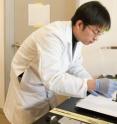 Bing Hu, a Stanford University post-doctoral fellow, prepares a small square of ordinary paper to with an ink that will deposit nanotubes on the surface that can then be charged with energy to create a battery.